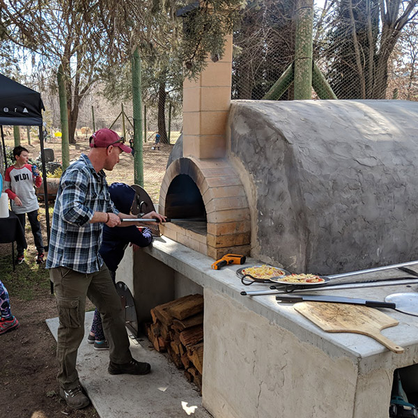 A man cooking pizza in a woodfired oven